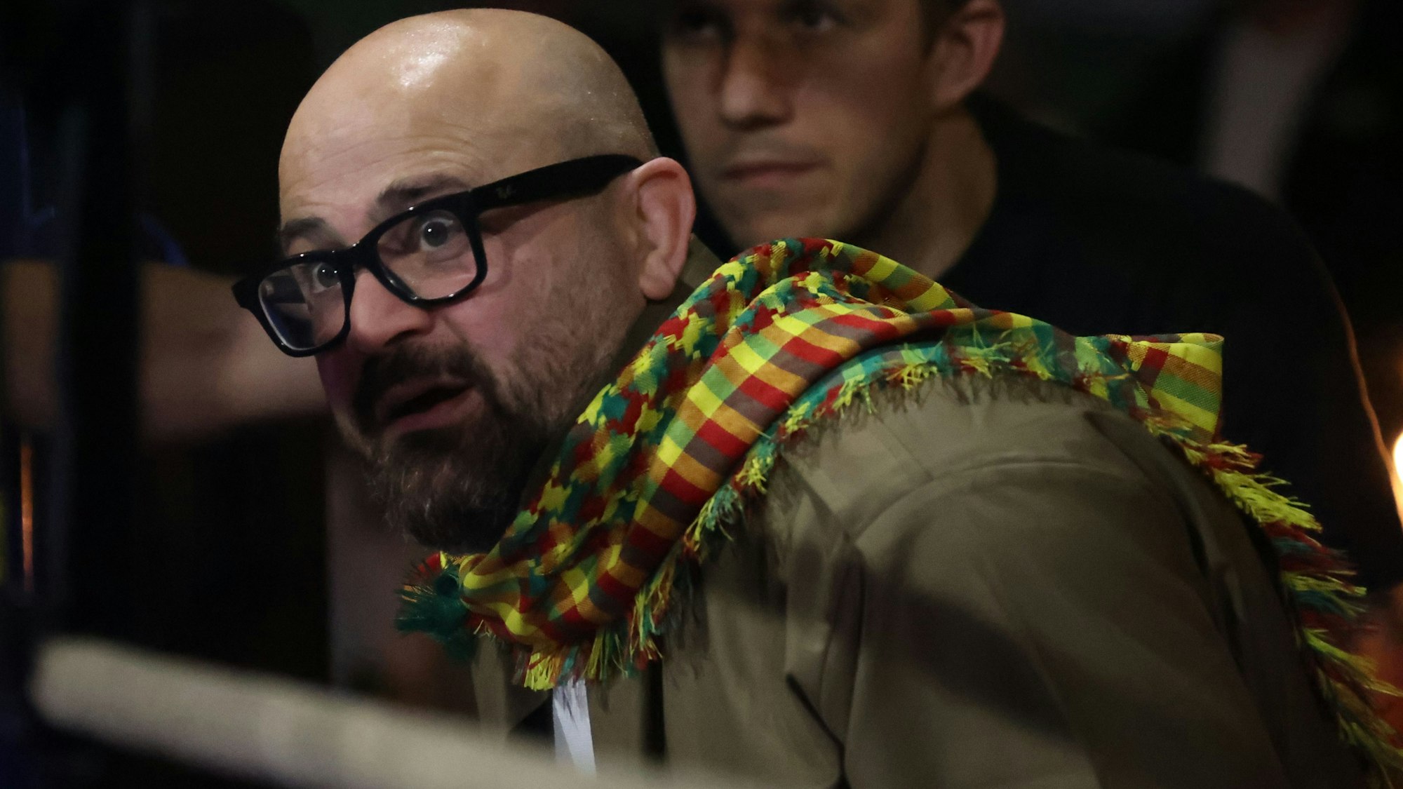 Bakar Barakat schaut mit aufgerissenen Augen in den Ring. Er trägt einen auffällig bunten Schal.