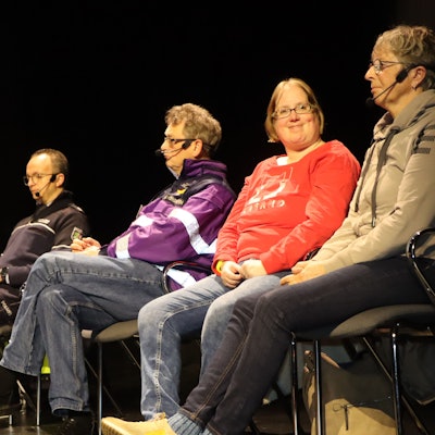 Auf dem Foto sind drei Frauen und ein Mann zu sehen, die auf einer Bühne auf Stühlen sitzen.