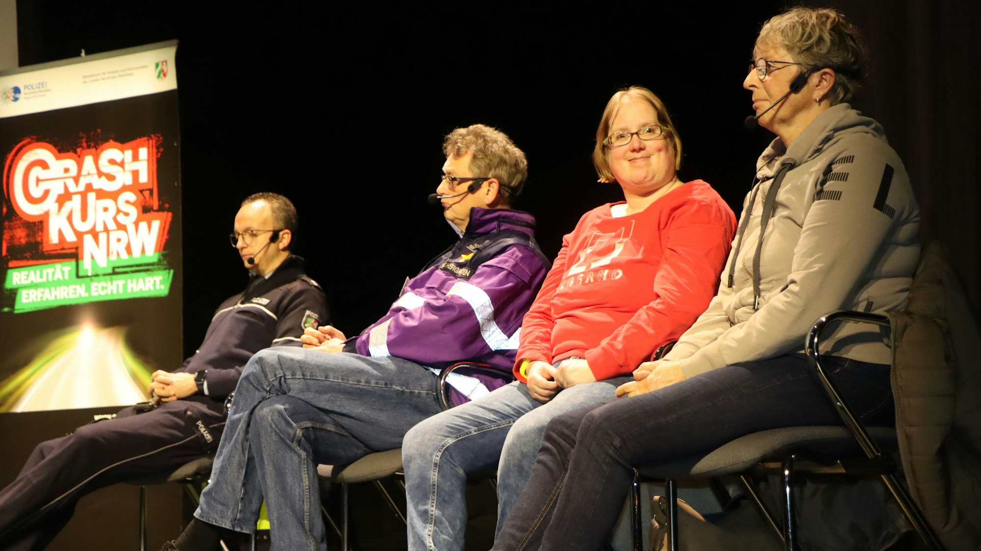 Auf dem Foto sind drei Frauen und ein Mann zu sehen, die auf einer Bühne auf Stühlen sitzen.