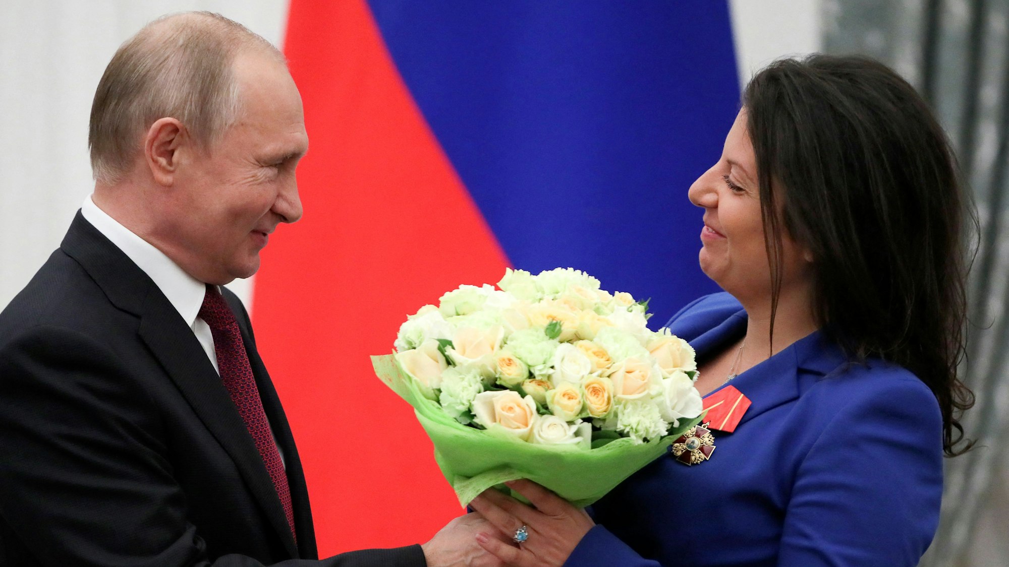 Margarita Simonjan (r.) bekommt Blumen von Kremlchef Wladimir Putin. Die Chefin des Propagandasenders „RT“ hat sich am Wochenende über misshandelte ukrainische Kriegsgefangene lustig gemacht. (Archvbild)