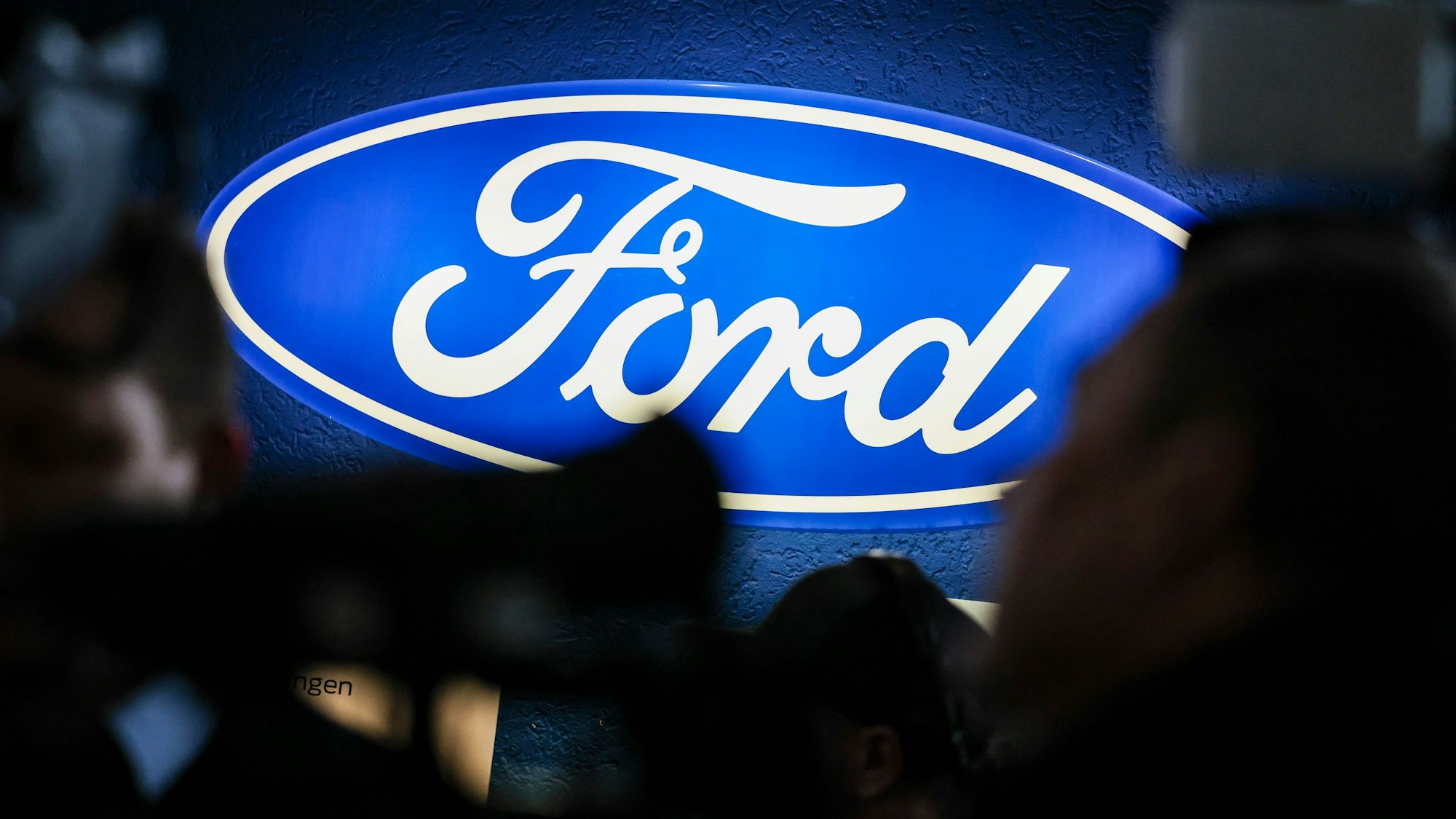 10.12.2024, Nordrhein-Westfalen, Köln: Ein beleuchtetes Firmenschild des Autobauers Ford leuchtet am Rande einer Betriebsversammlung am Standort Köln. Nach der Bekanntgabe eines weitreichenden Stellenabbaus beim Autobauer Ford in Köln sprach auch Bundeskanzler Scholz zu den Beschäftigten, von denen viele um ihre Jobs bangen. Foto: Christoph Reichwein/dpa +++ dpa-Bildfunk +++