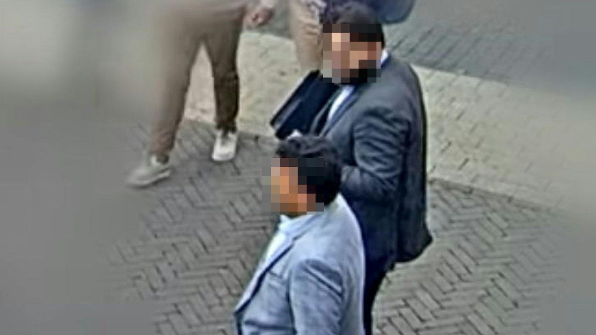 Auf dem Foto aus einer Überwachungskamera sind zwei Männer in Anzügen zu sehen. Ihre Gesichter wurden nachträglich gepixelt.
