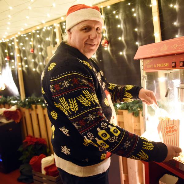 Ralf Haase füllt Popcorn in eine Tüte. Er trägt eine Nikolausmütze und einen Weihnachtspullover.