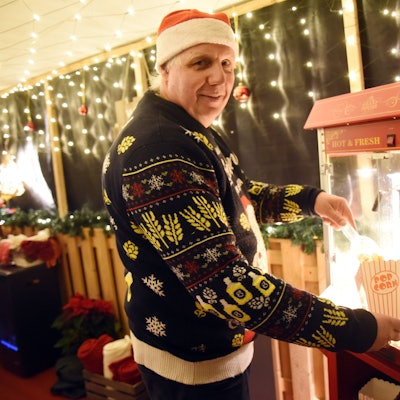 Ralf Haase füllt Popcorn in eine Tüte. Er trägt eine Nikolausmütze und einen Weihnachtspullover.