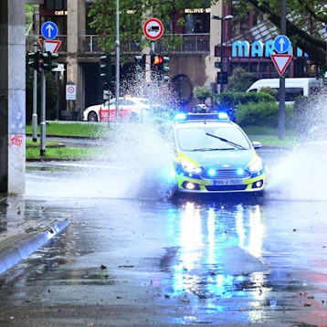 Auf der Straße Vor St. Martin hat sich eine Menge Wasser angesammelt. Ein Polizei Fahrzeug fährt mit Blaulicht durch.