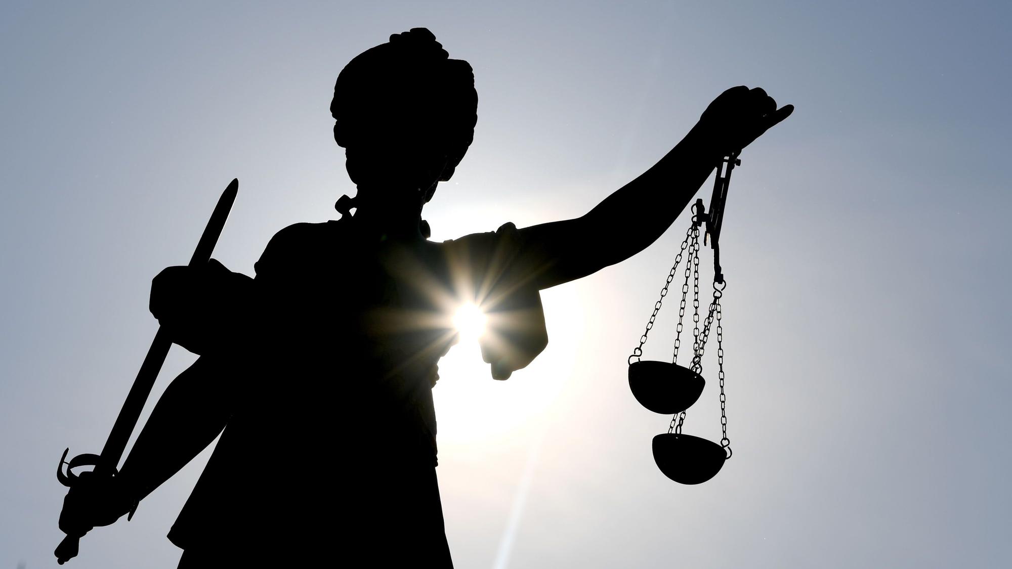 Eine Statue der Göttin Justitia im Gegenlicht.