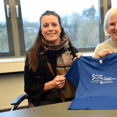 Das Foto zeigt zwei Frauen und ein blaues T-Shirt mit dem Logo des Projekts "Die schwimmenden Pferdchen".