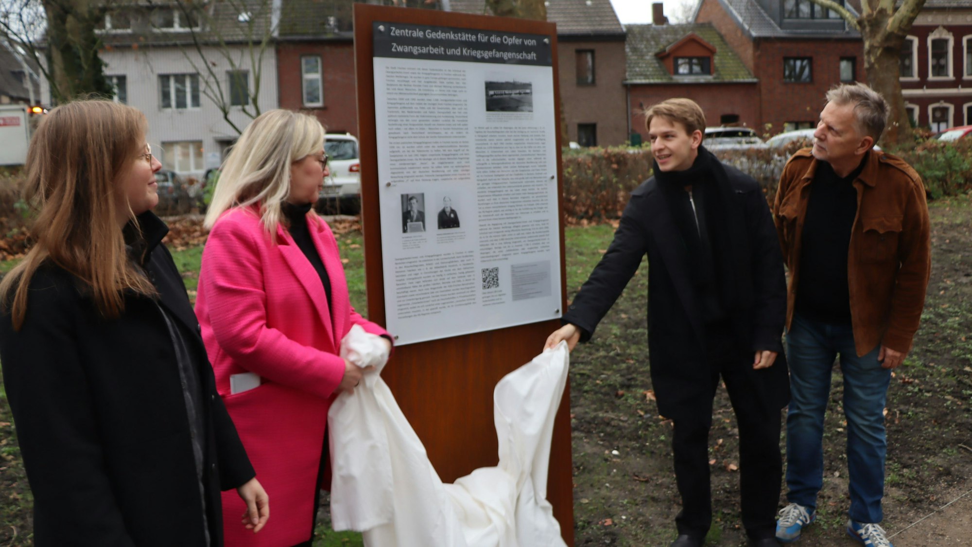 Auf dem Bild sind zwei Frauen und zwei Männer zu sehen, die eine Gedenktafel enthüllen.