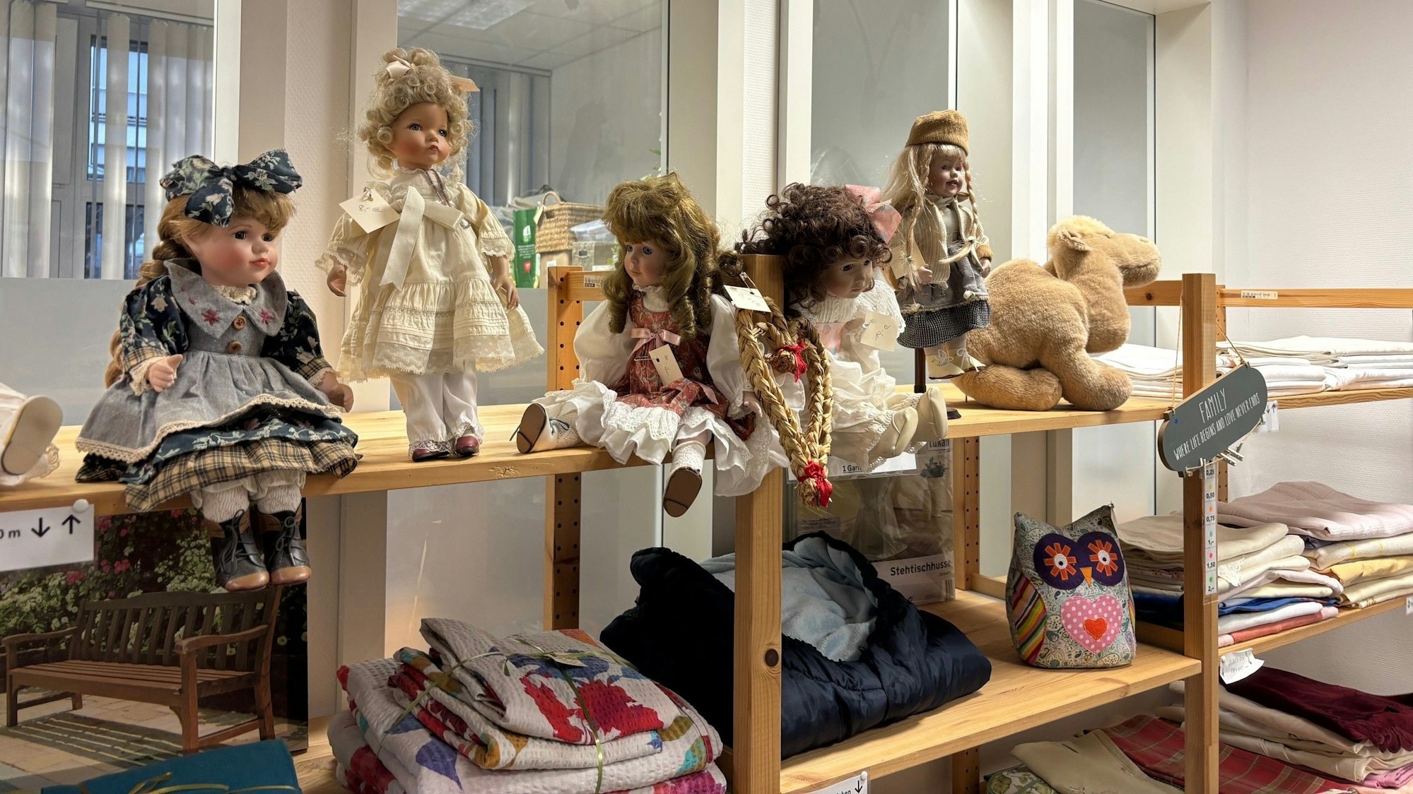 Auf dem Bild ist ein Holzregal mit gespendeten Puppen und Wäsche zu sehen.