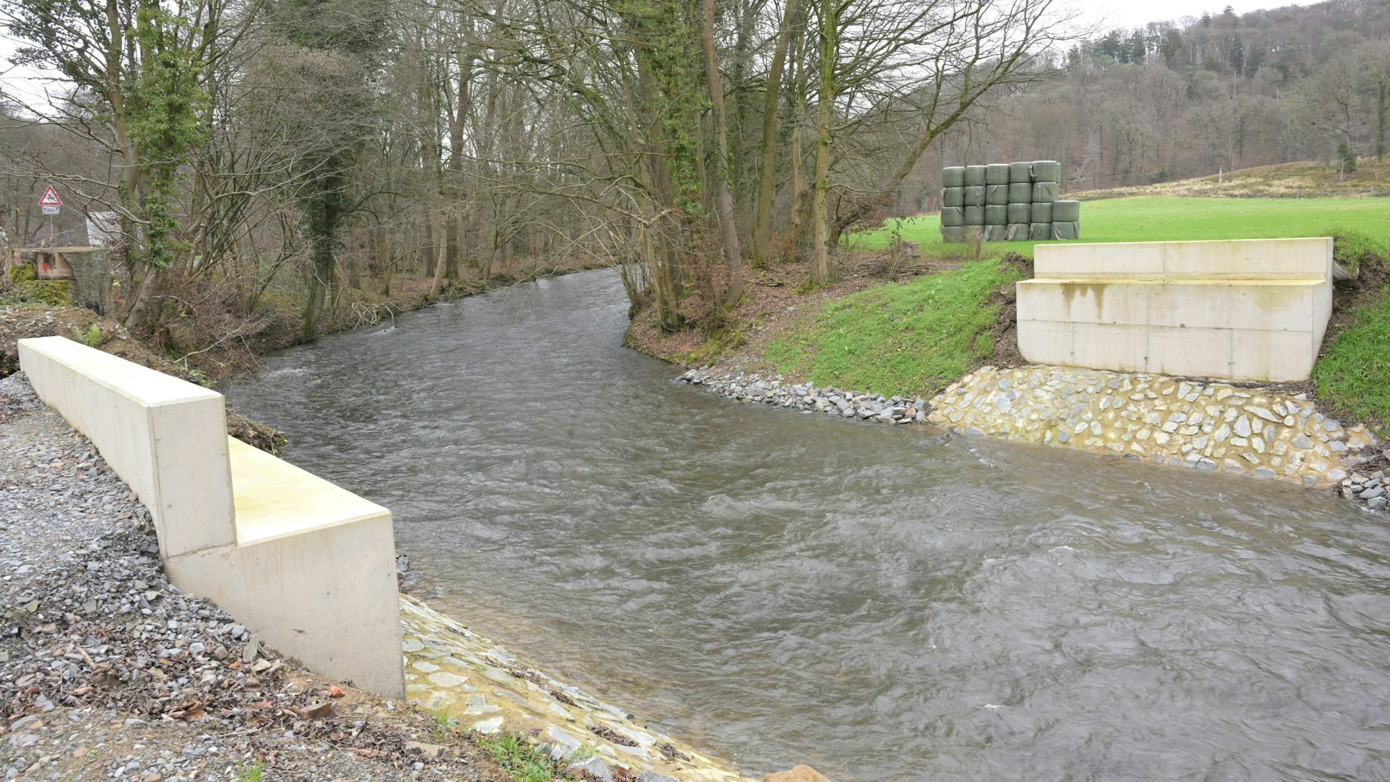 Ein Fluss, rechts und links am Ufer Brückenstützen, die Brücke fehlt noch.