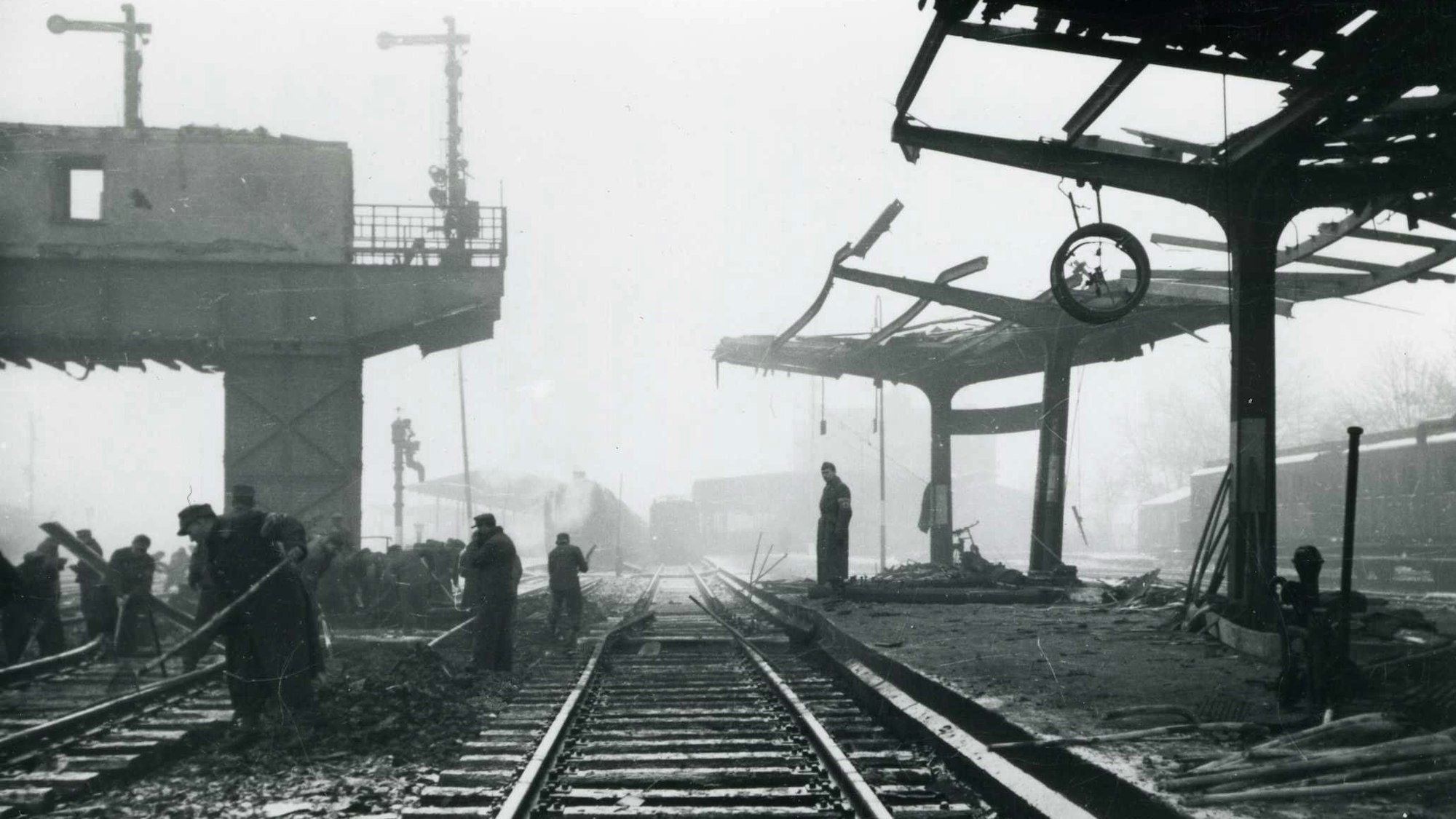 Menschen räumen an einem Bahnhof auf, der nach Bombardierungen im Zweiten Weltkrieg stark beschädigt wurde.