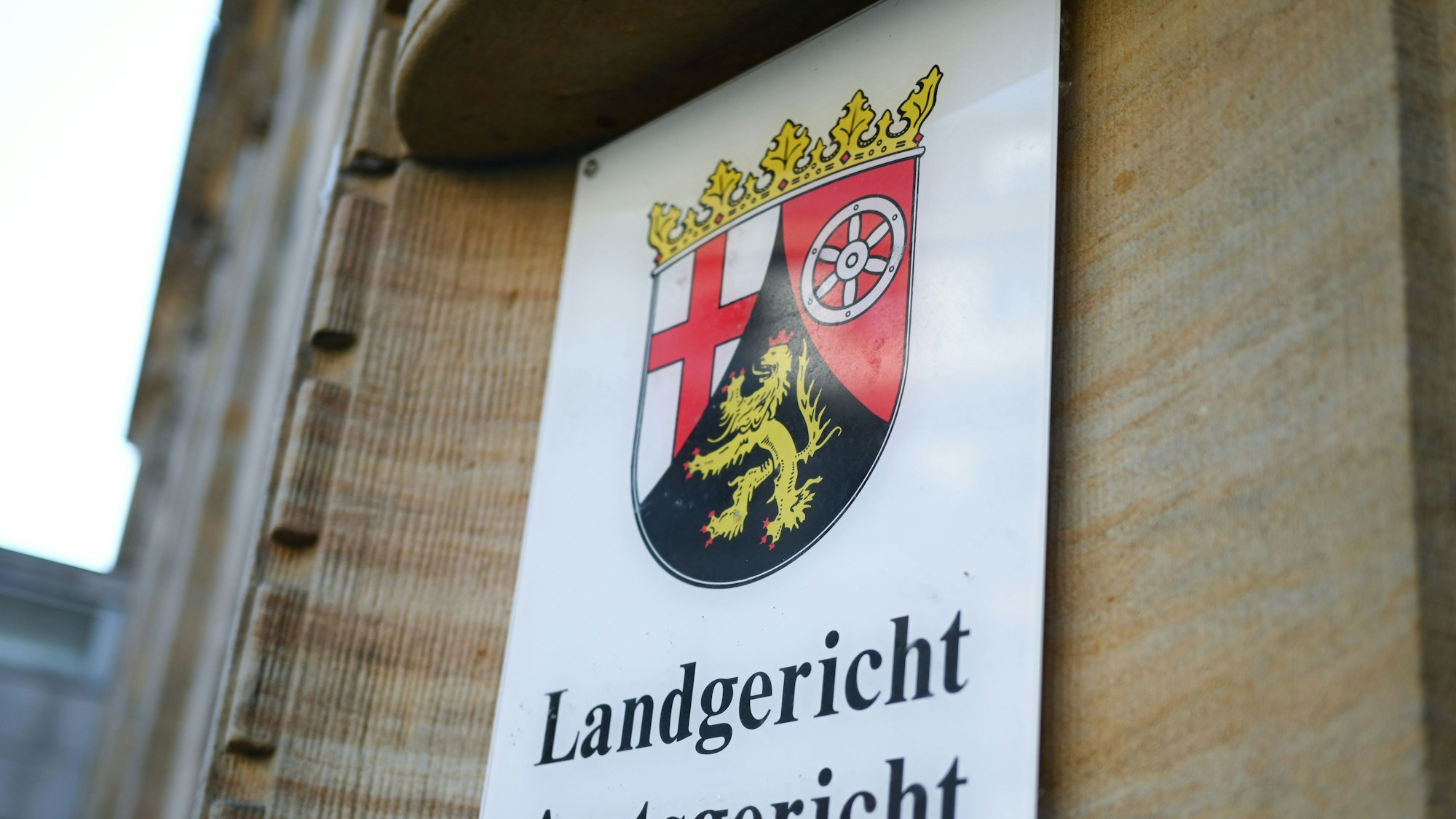 Ein Schild mit dem Landeswappen von Rheinland-Pfalz an der Fassade des Landgerichts.