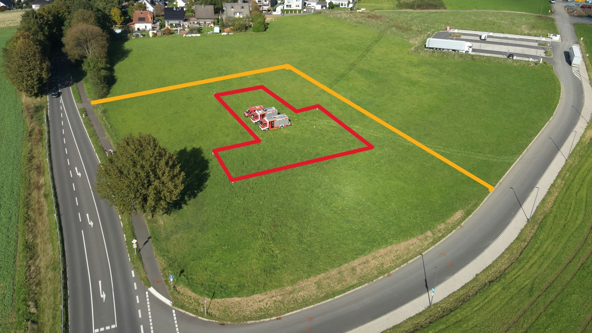 Drei Feuerwehrautos stehen auf einer Wiese, auf der das neue Feuerwehrgerätehaus gebaut werden soll.