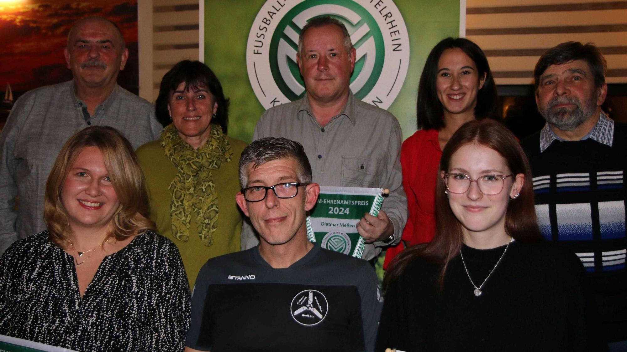 Acht Menschen stehen vor einem Logo des Fußballkreises Euskirchen.
