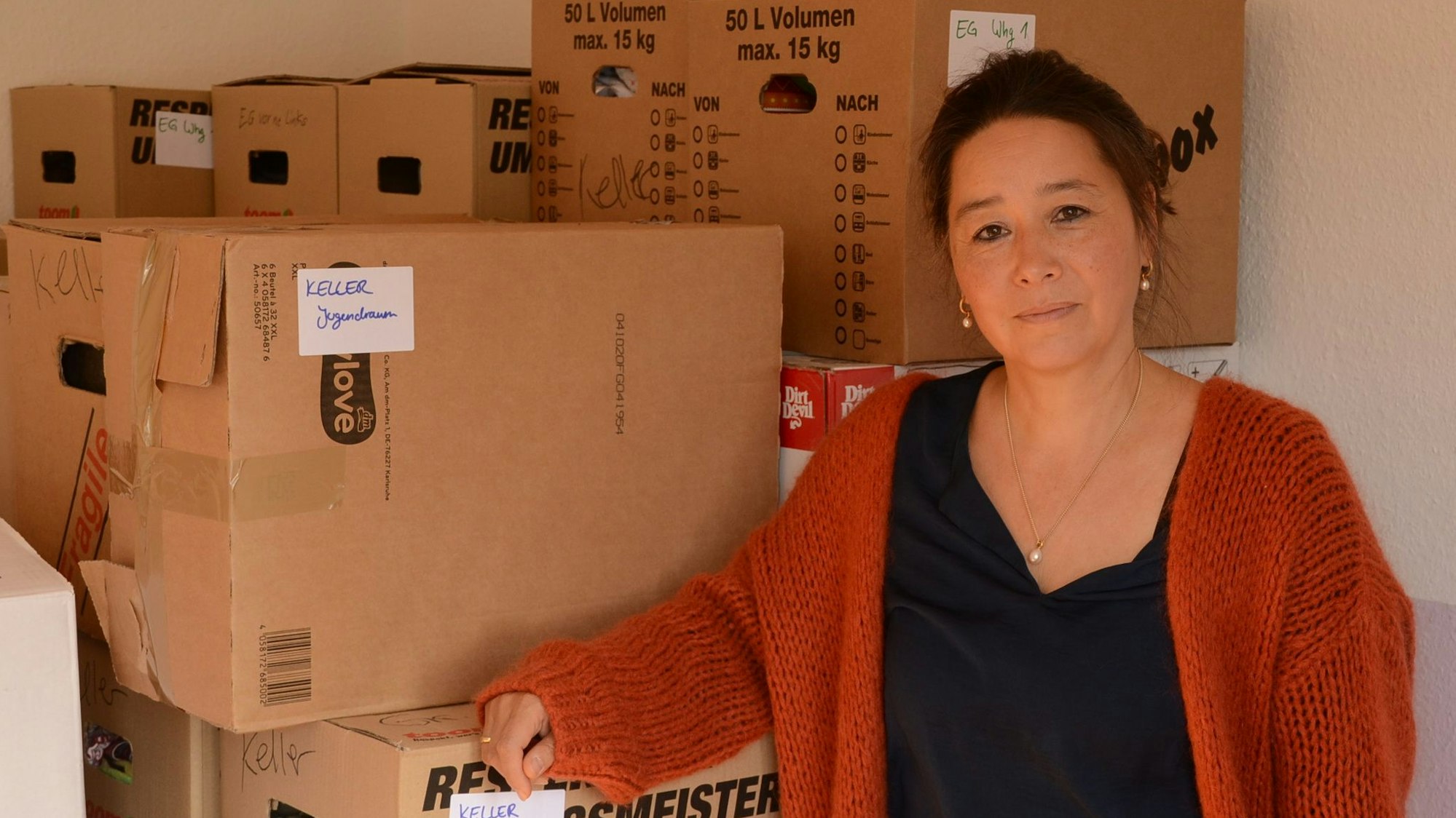 Eine Frau steht vor einem Stapel von Umzugskartons.