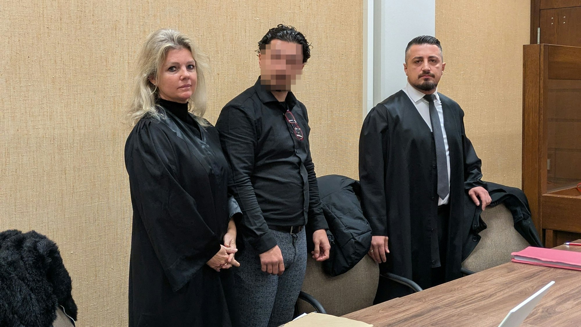 Ein in einem Strafverfahren angeklagter Mann mit zwei Verteidigern.