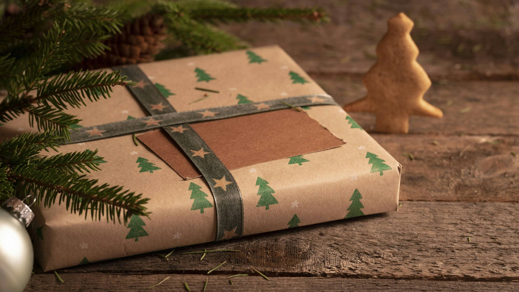 Geschenkkarton in braunem klassischem Papier mit Weihnachtsbaummuster, Tannenzweigen, Weihnachtskugel und Weihnachtsbaumkeksen auf einem rustikalen Tisch Gift box wrapped in brown classic paper and Christmas trees design, fir twigs, Xmas ball, and a Christmas tree cookie, on a rustic table Copyright: imageBROKER/AndreixUreche ibxiqx11334483.jpg Bitte beachten Sie die gesetzlichen Bestimmungen des deutschen Urheberrechtes hinsichtlich der Namensnennung des Fotografen im direkten Umfeld der Veröffentlichung