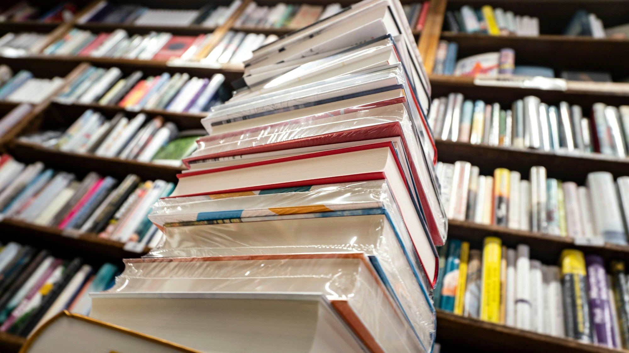 Ein Stapel neuer Bücher liegt auf einem Verkaufstisch in einer Buchhandlung.