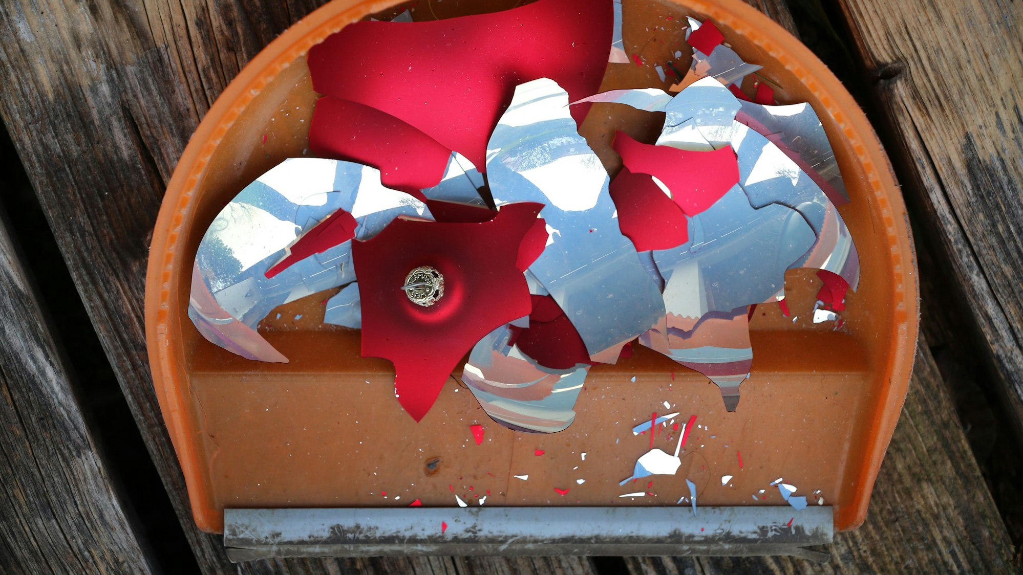 Scherben einer Weihnachtskugel liegen aufgekehrt in einer Handschaufel.
