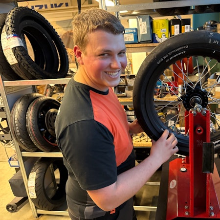 Ein junger Mann hantiert mit einem Motorradreifen.