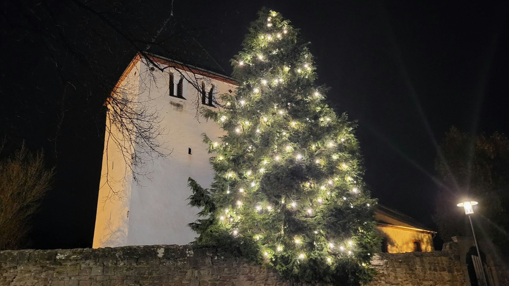 Ein Weihnachtsbaum leuchtet an der Alten Kirche in Mechernich.