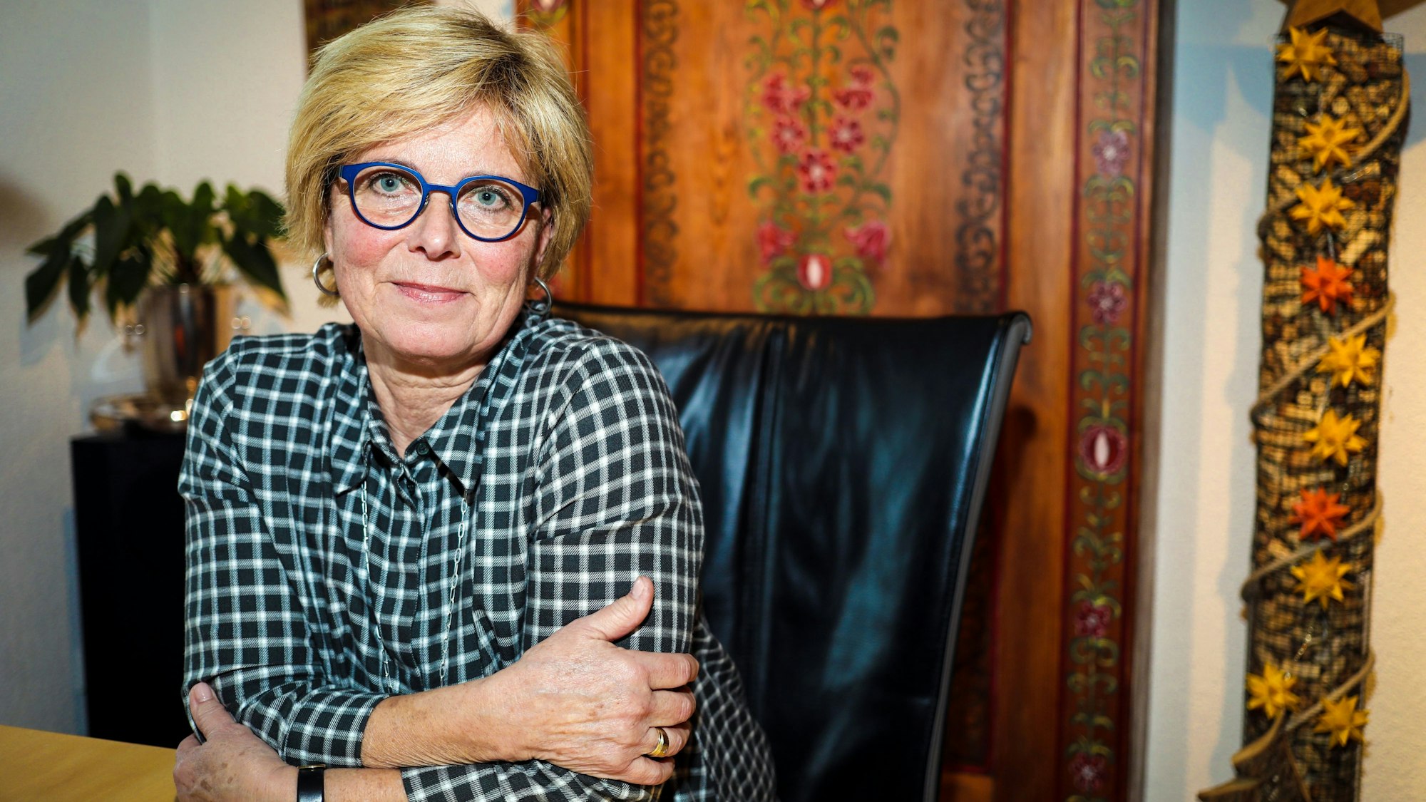 Verena Welschof sitzt zuhause an einem Esstisch und lächelt in die Kamera. Sie sieht frisch und gut aus.