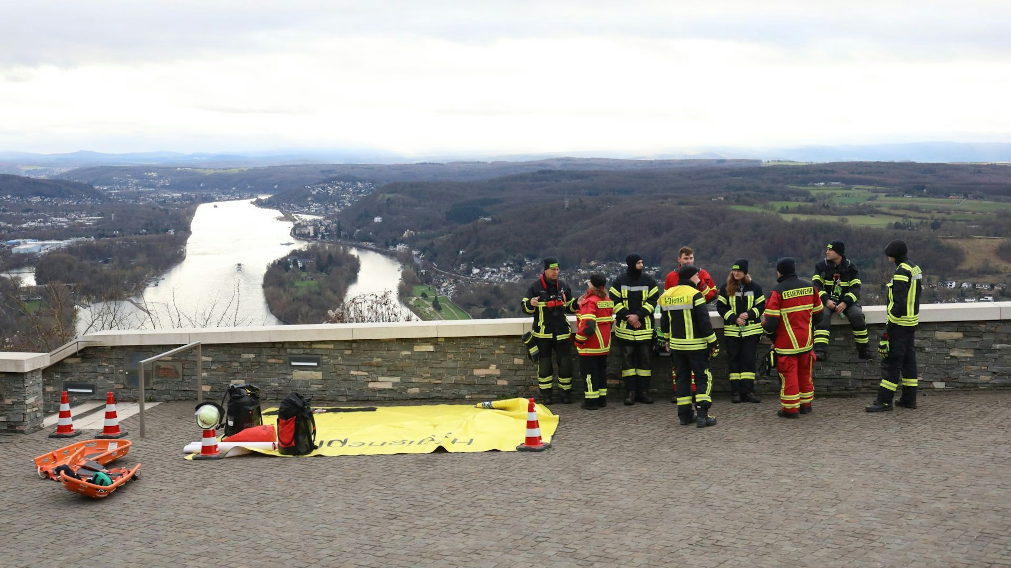 Einsatzkräfte stehen auf dem Drachenfelsplateau mit Blick auf den Rhein.