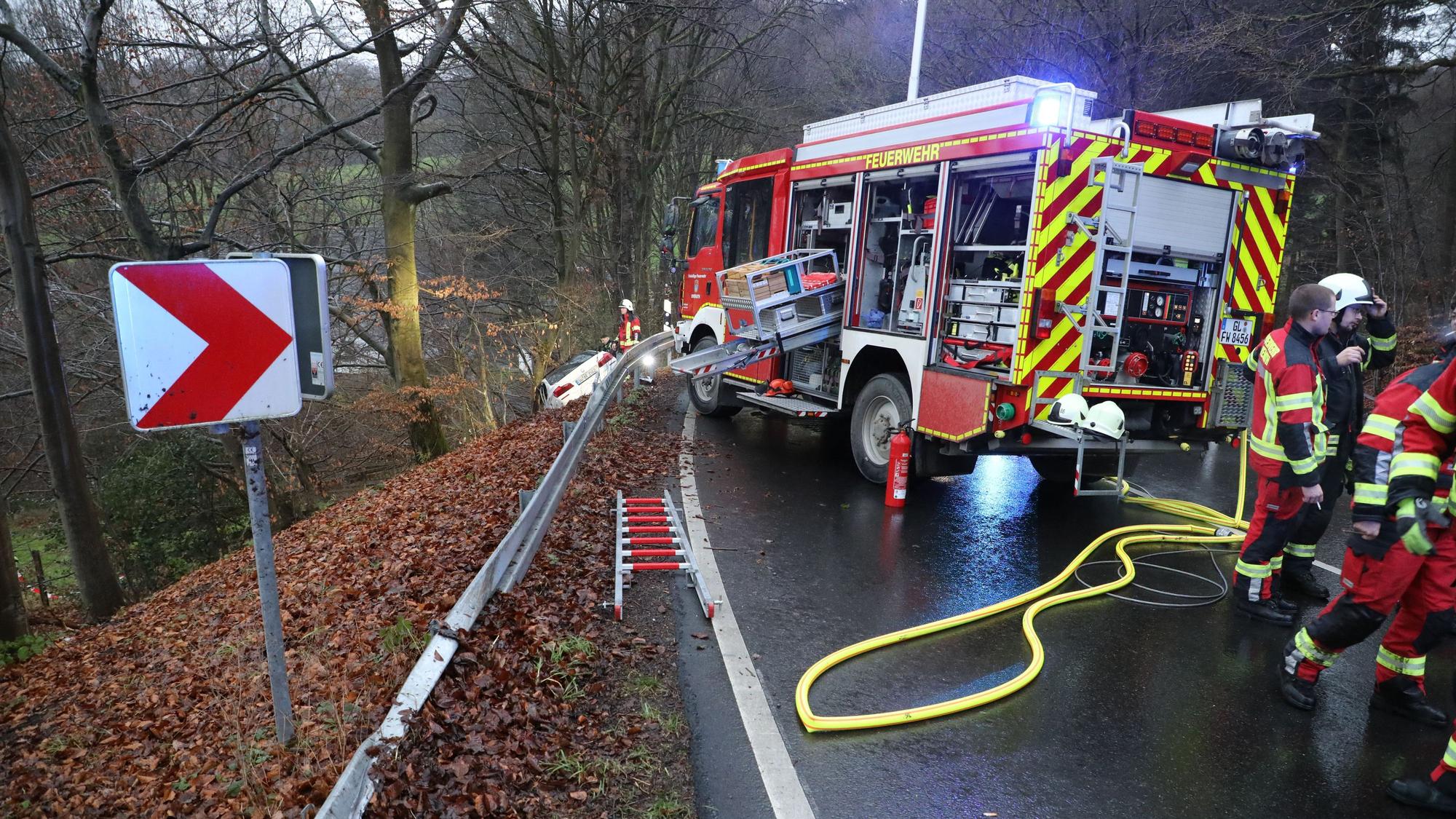 Eine demolierte Leitplanke ist an der Mucher Straße zu sehen, auf der Fahrbahn steht ein Feuerwehrfahrzeug.