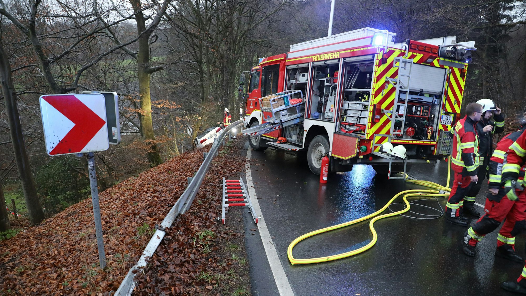 Eine demolierte Leitplanke ist an der Mucher Straße zu sehen, auf der Fahrbahn steht ein Feuerwehrfahrzeug.