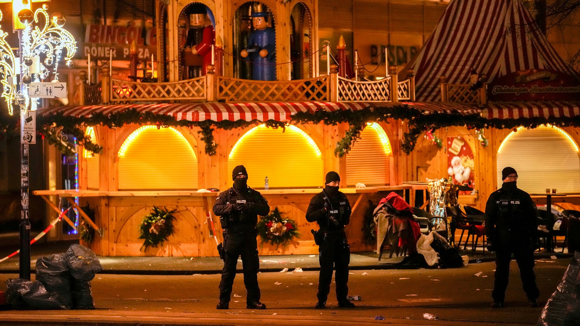 Sicherheitskräfte stehen vor einem abgesperrten Weihnachtsmarkt, nachdem ein Auto in eine Menschenmenge gerast ist, in Magdeburg