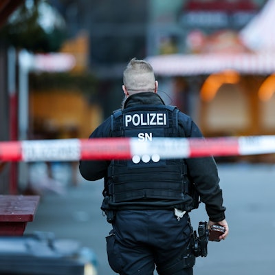 Ein Polizist steht hinter einer Absperrung am Magdeburger Weihnachtsmarkt. Am Vorabend war ein Autofahrer in eine Menschengruppe gefahren. Es gab mehrere Tote und Verletzte.