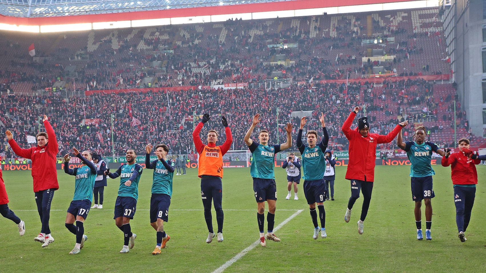 Die Spieler des 1.FC Kölns bejubeln den Sieg vor der Fankurve.