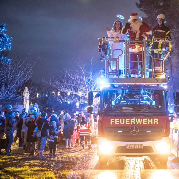 Bunt beleuchtete Einsatzfahrzeuge fuhren in Kolonne durch den Park des Klinikums in Leverkusen.