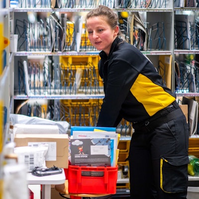 Das Bild zeigt die Post-Mitarbeiterin, während sie Briefe sortiert.