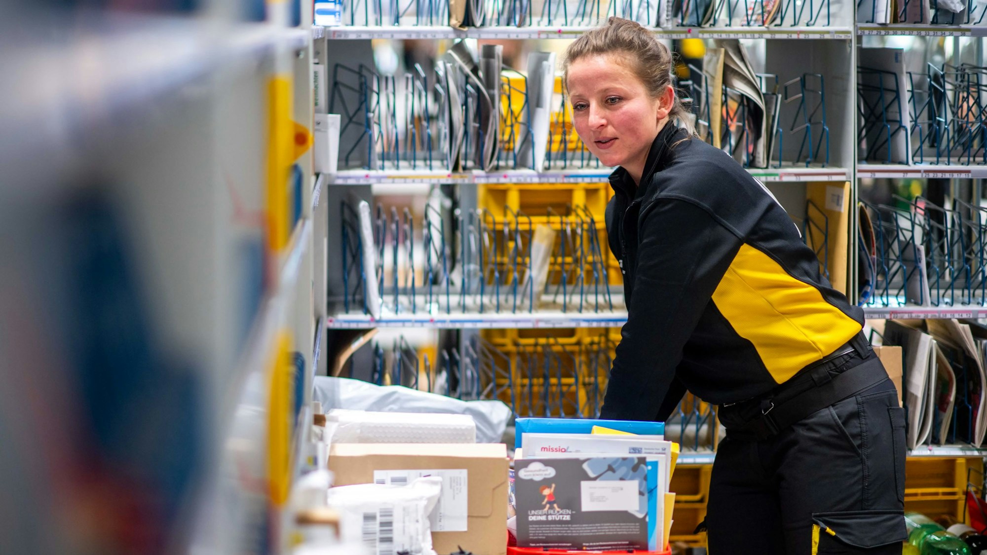 Das Bild zeigt die Post-Mitarbeiterin, während sie Briefe sortiert.