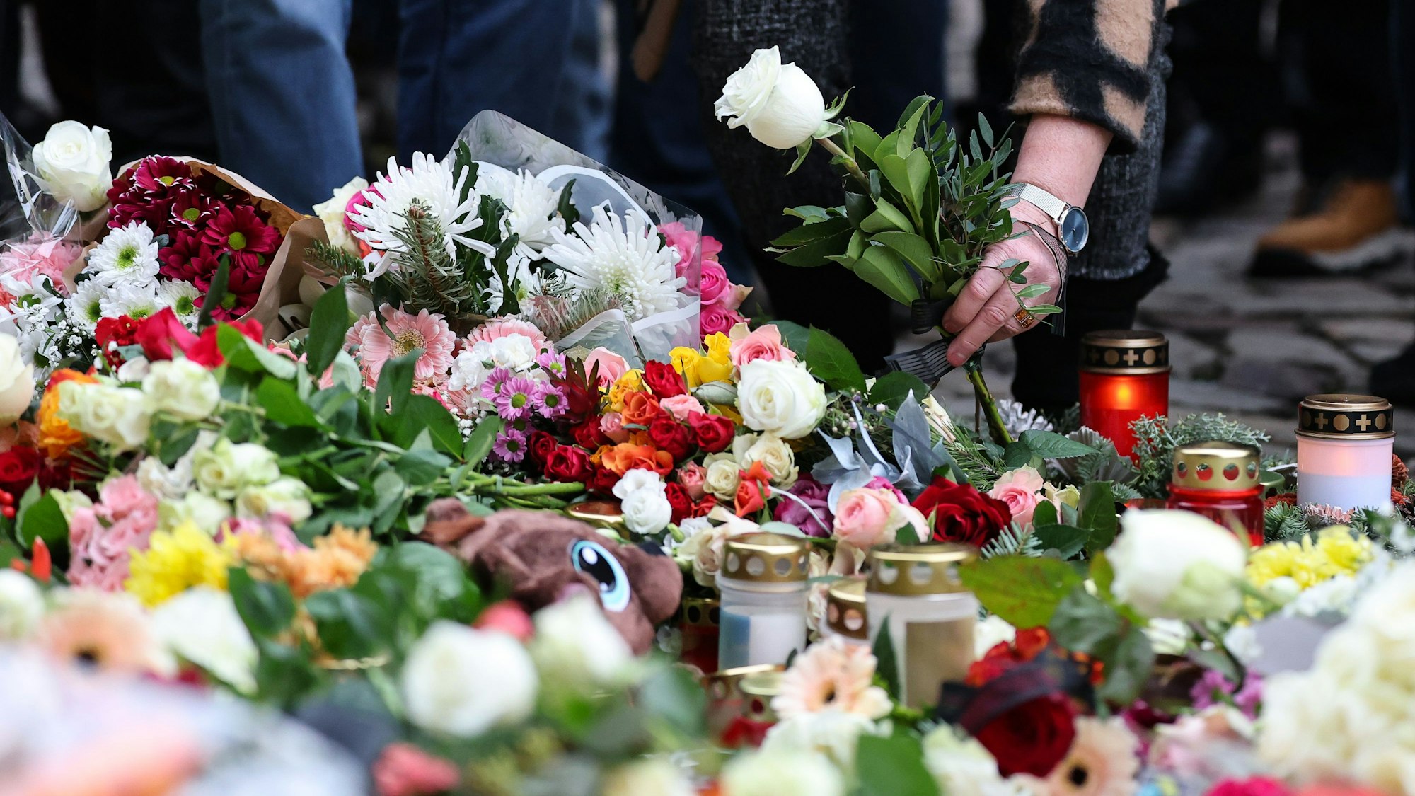 21.12.2024, Sachsen-Anhalt, Magdeburg: Eine Frau legt Blumen am offiziellen Gedenkort an der Johanniskirche nieder. Am Vorabend war ein Autofahrer auf dem Magdeburger Weihnachtsmarkt in eine Menschengruppe gefahren. Foto: Jan Woitas/dpa