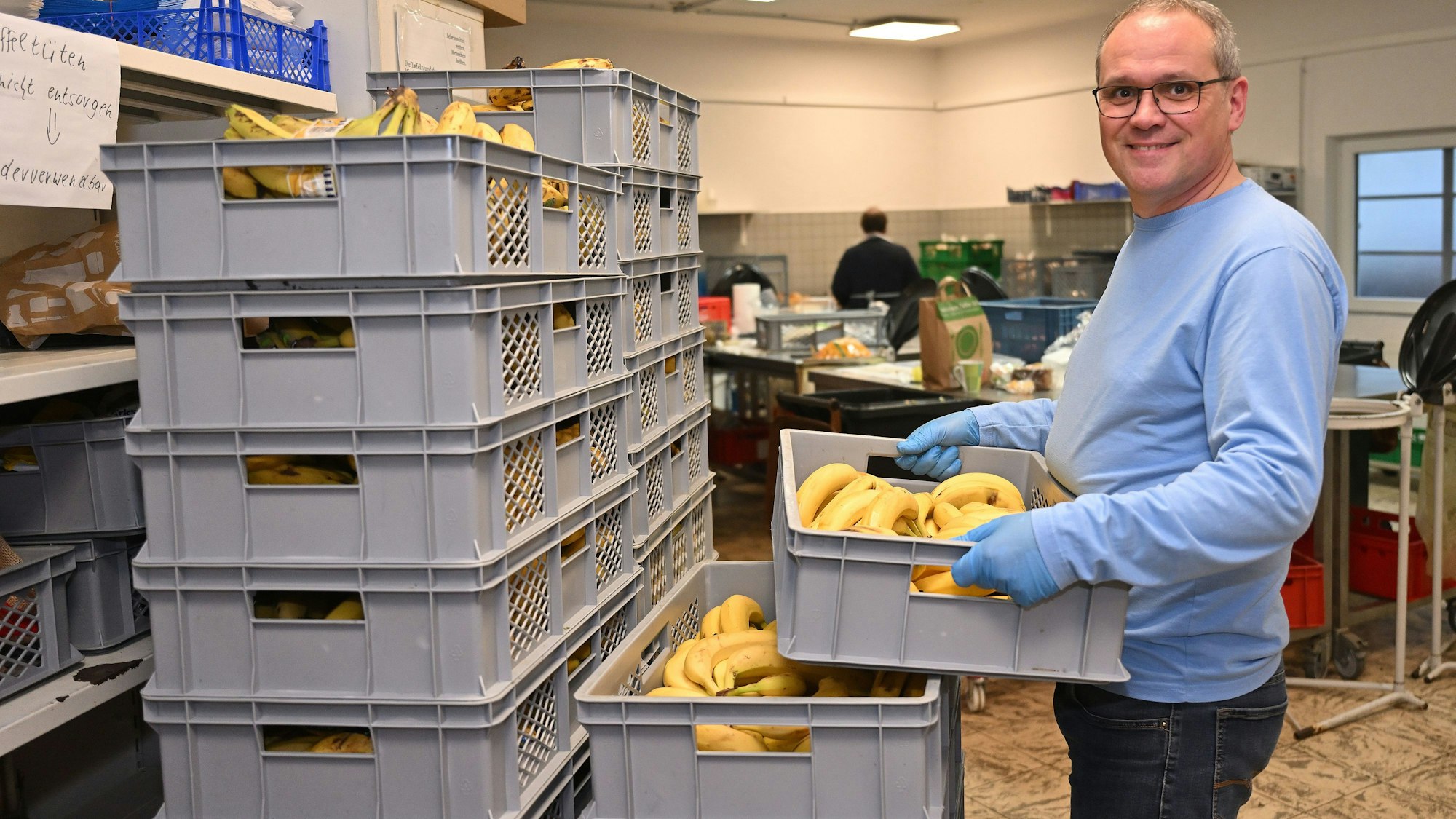 Der Helfer hält eine Kiste mit Bananen in den Händen.
