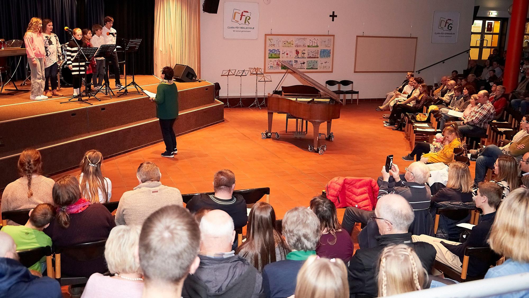 Blick in die voll besetzte Aula des Clara-Fey-Gymnasiums, auf der Bühne stehen Kinder.