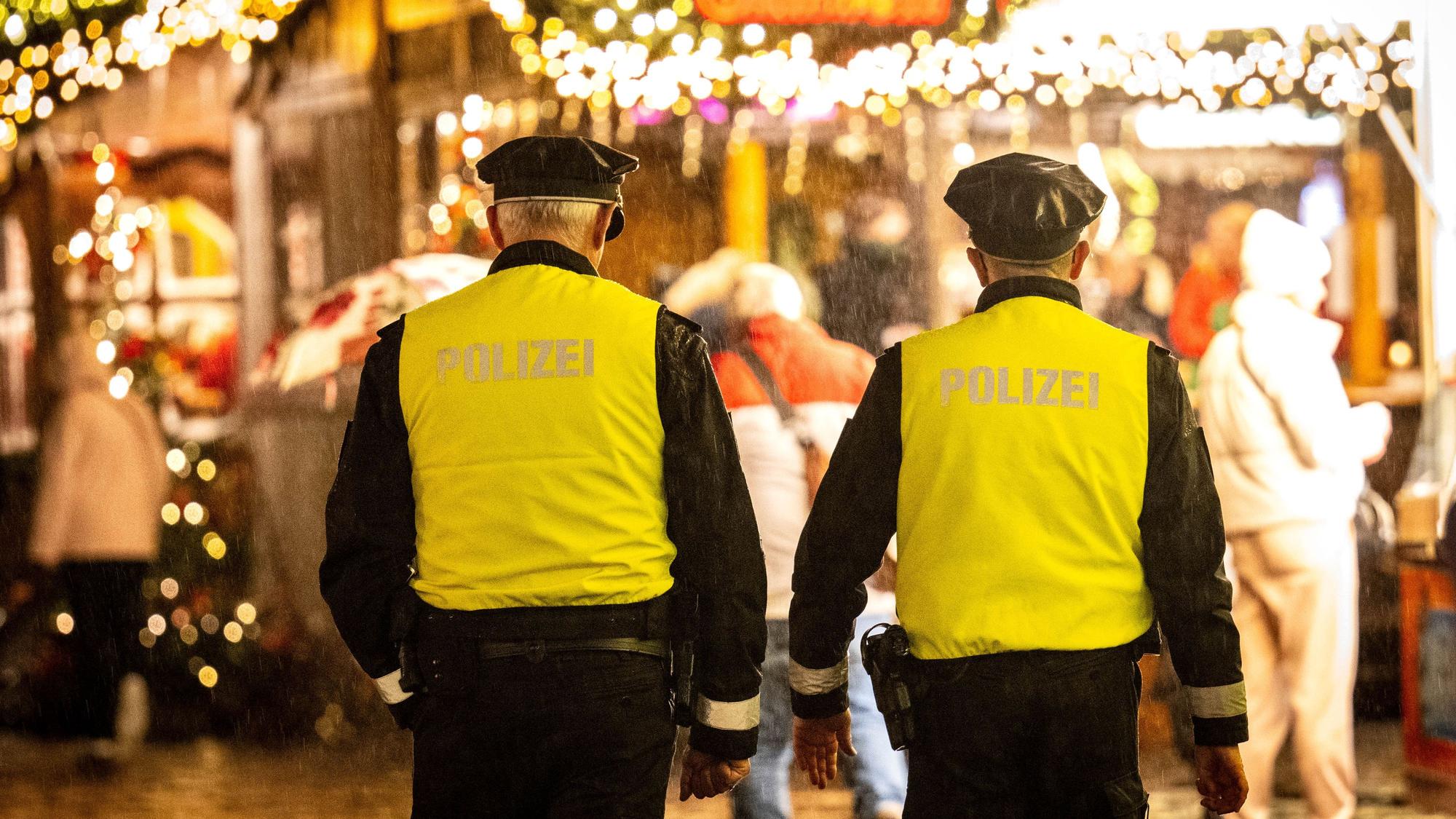 Einsatzkräfte der Polizei laufen über einen Weihnachtsmarkt. (Symbolbild)