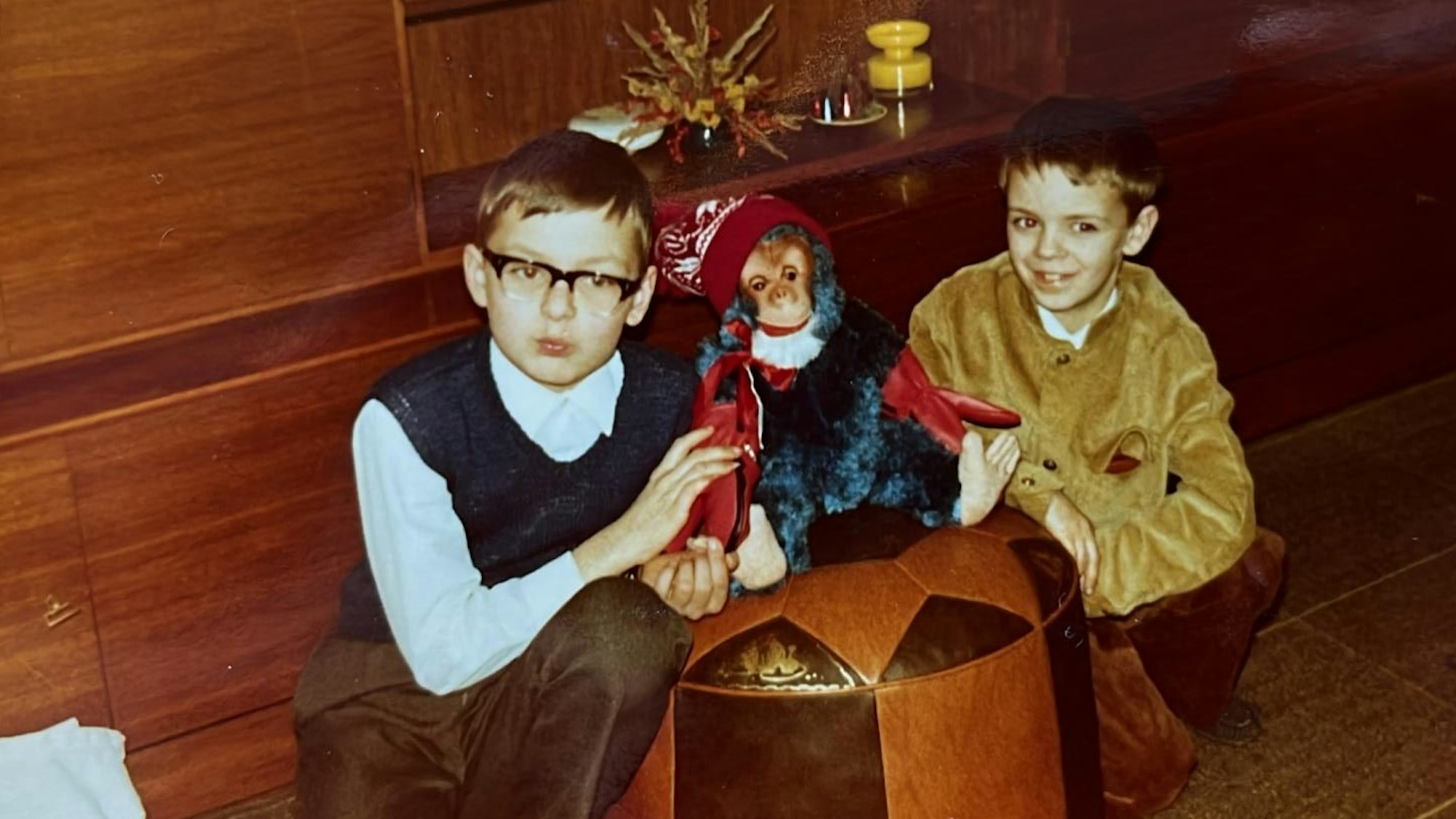 Zwei Jungs hocken auf dem Boden, zwischen ihnen ein Plüschaffe.