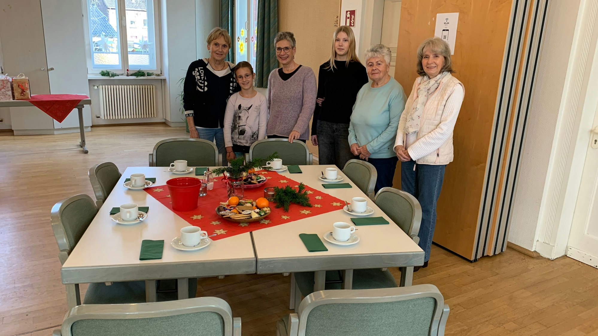 Eine Gruppe von Frauen und Mädchen vor einem gedeckten Tisch.