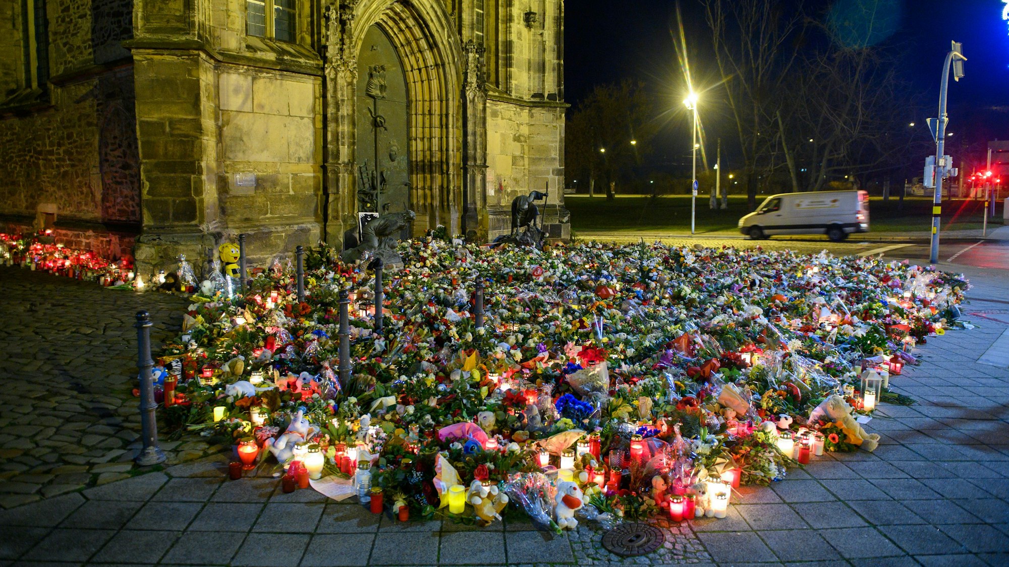 Blumen, Kerzen, Kränze und Stofftiere liegen vor der Johanniskirche in Magdeburg. Menschen gedenken hier den Opfern des Anschlags auf den Magdeburger Weihnachtsmarkt.