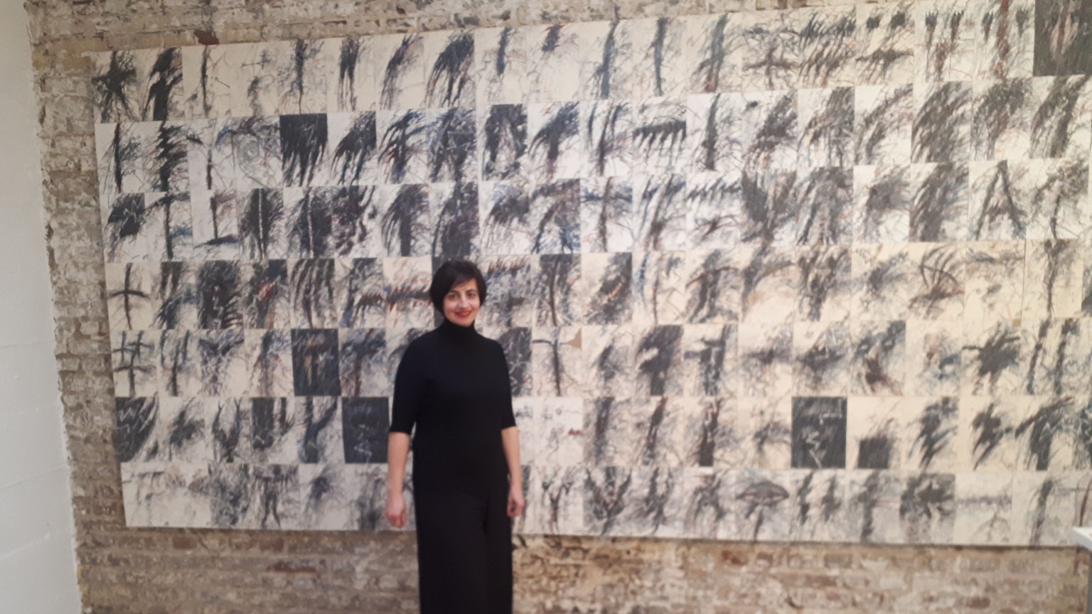 Janine Koppelmann, die Tochter der Atelier-Gründerin, vor der 140-teiligen Zeichnungsserie von Peter Gilles, entstanden im Eindruck des Attentats auf Ronald Reagan 1981.