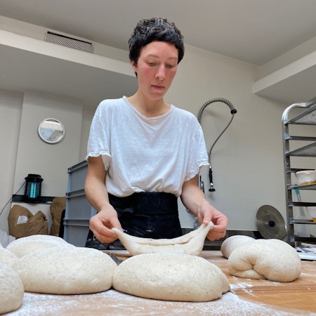 Zu sehen ist eine Frau, die Brotteig formt.