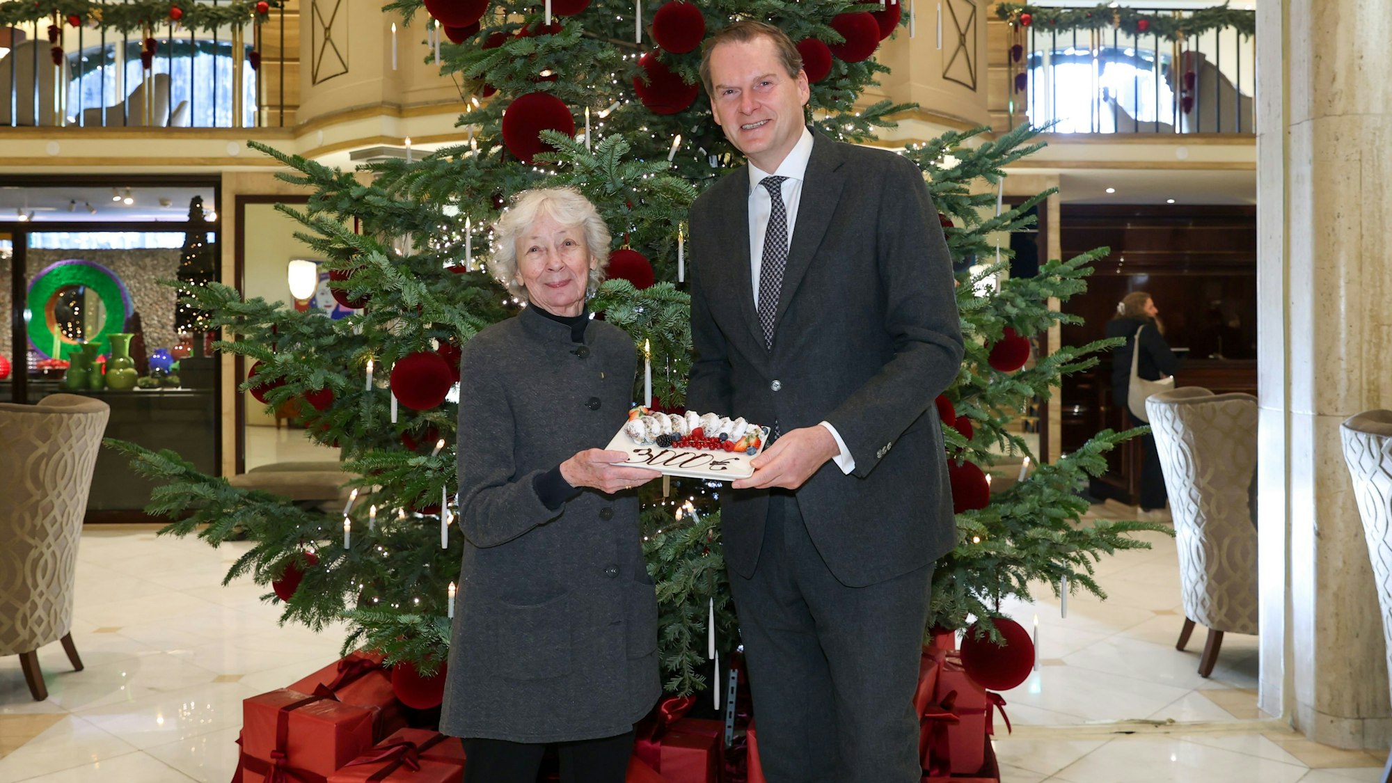 Symbolische Spendenübergabe im Excelsior-Foyer: Hoteldirektor Georg Plesser übergibt Hedwig Neven DuMont 3.000 Euro für „wir helfen“ in Form eines Stollens.