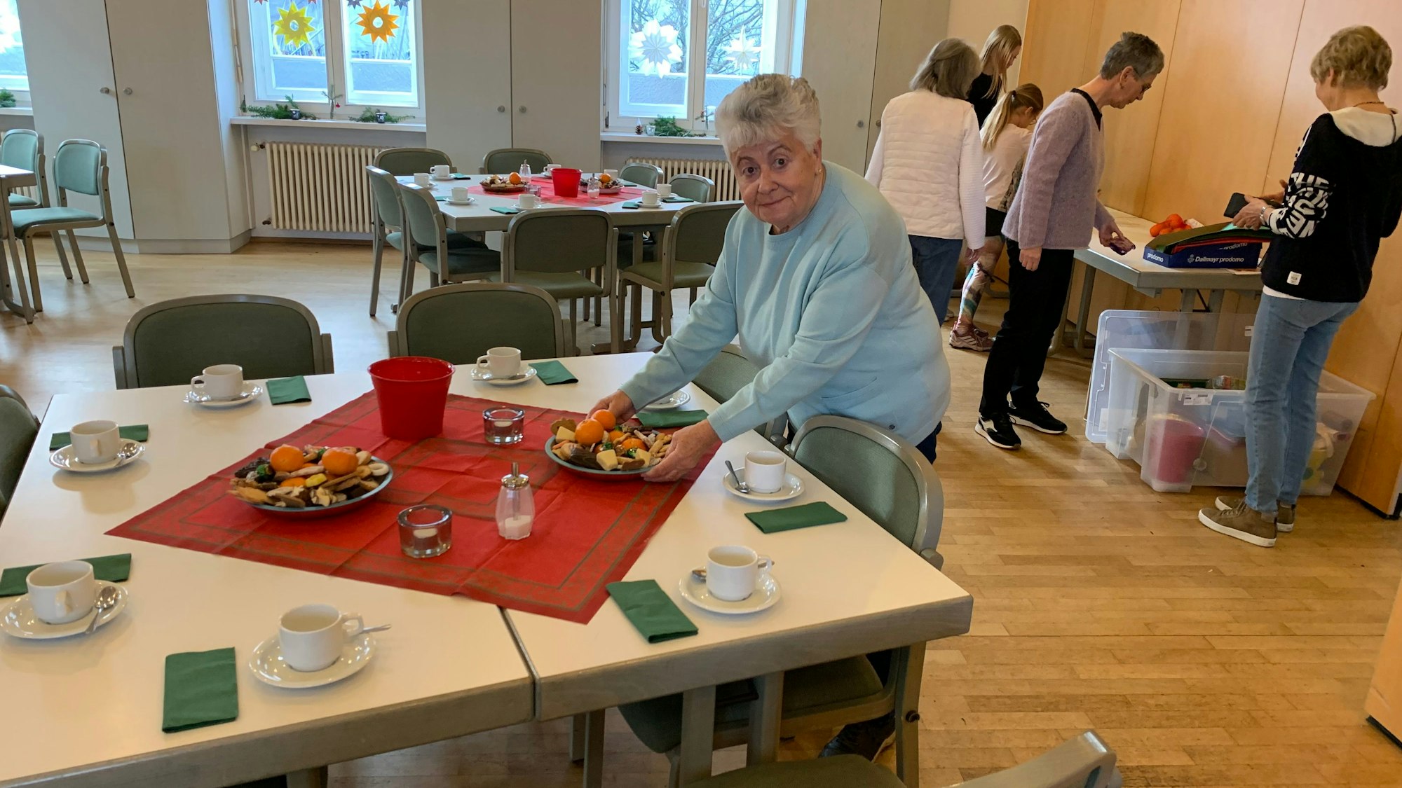 Eine Frau stellt einen Teller mit Weihnachtssüßigkeiten auf einen gedeckten Tisch.