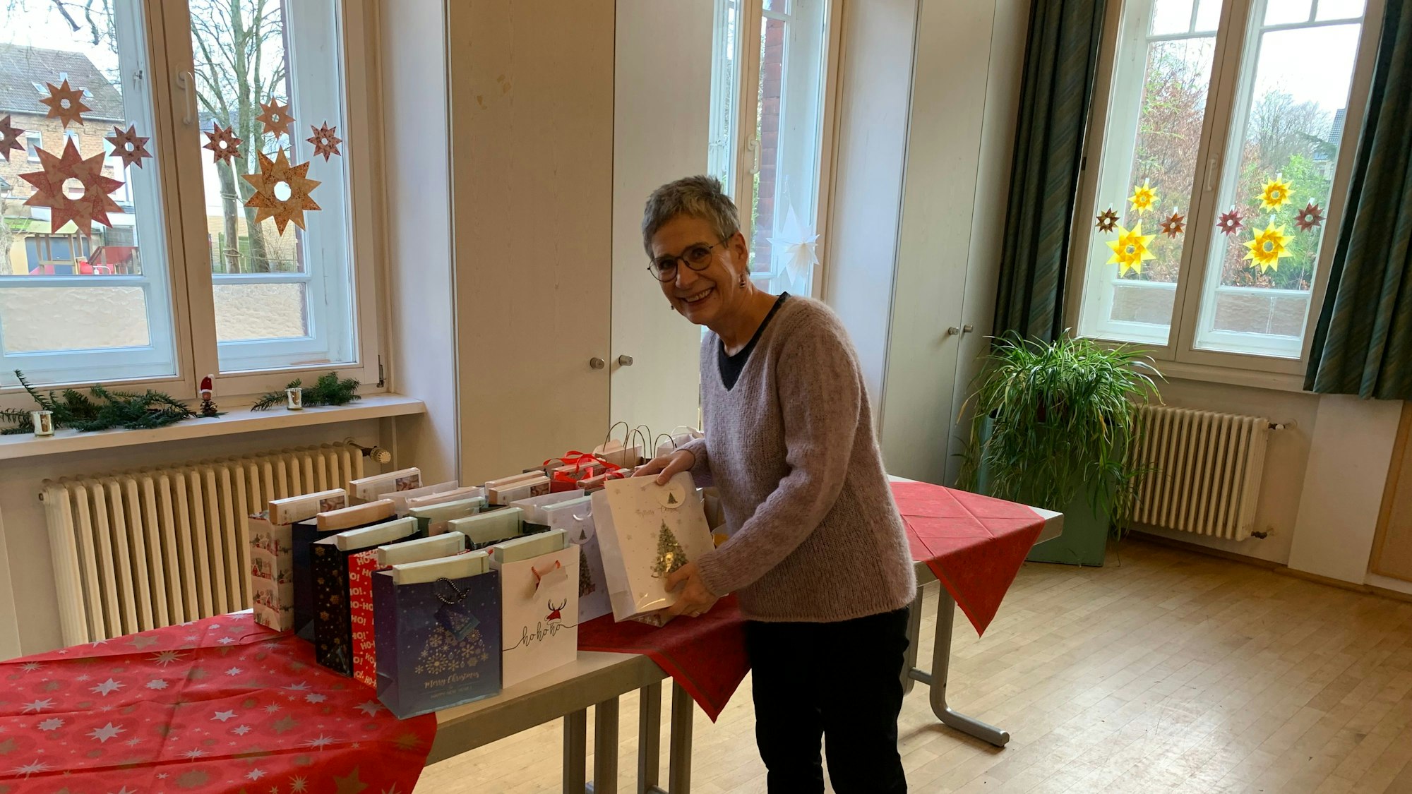 Eine Frau stellt eine Tüte mit Geschenken auf einen Tisch.
