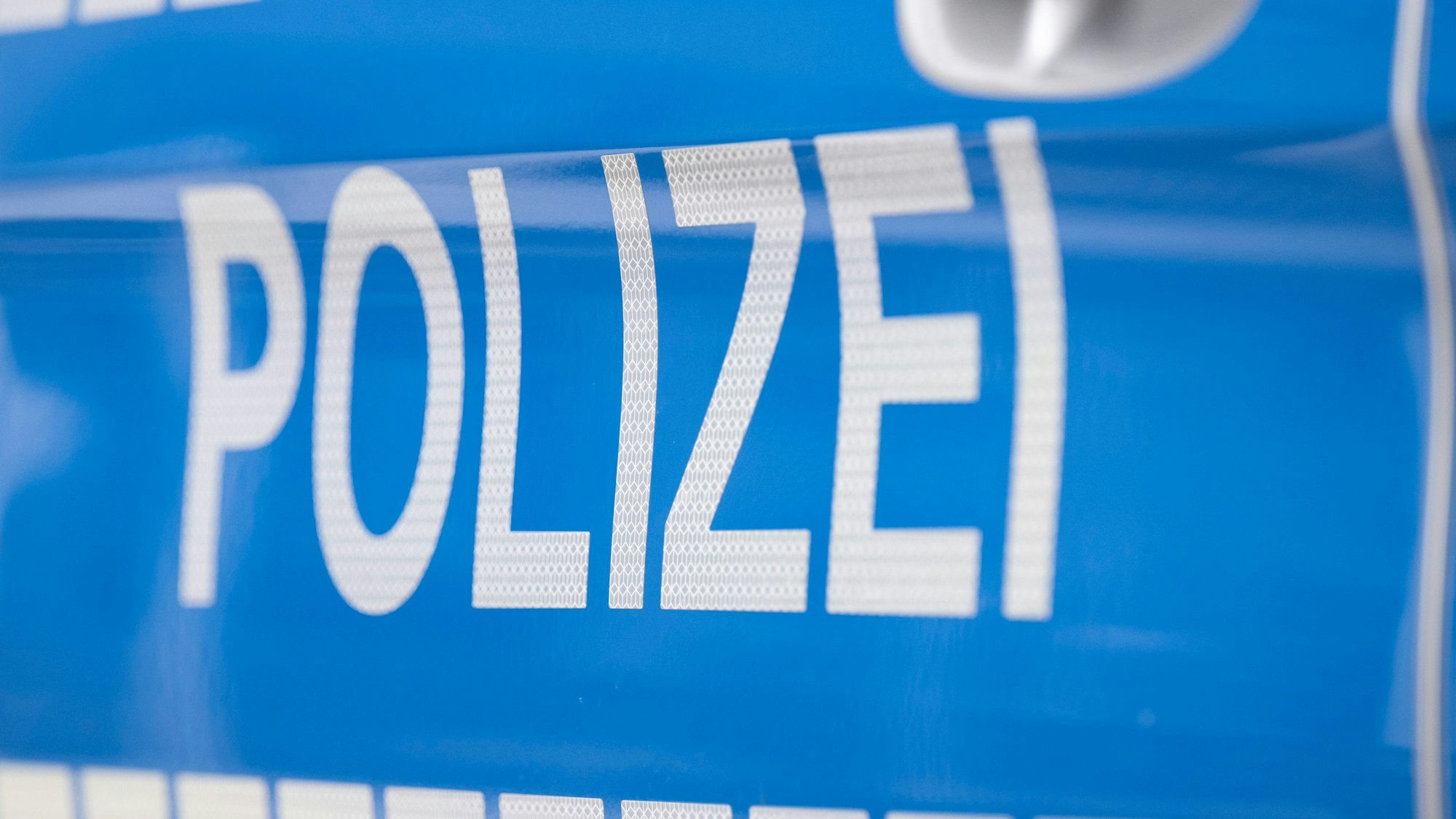 Das Foto zeigt den Schriftzug „Polizei“ auf einem Einsatzwagen.