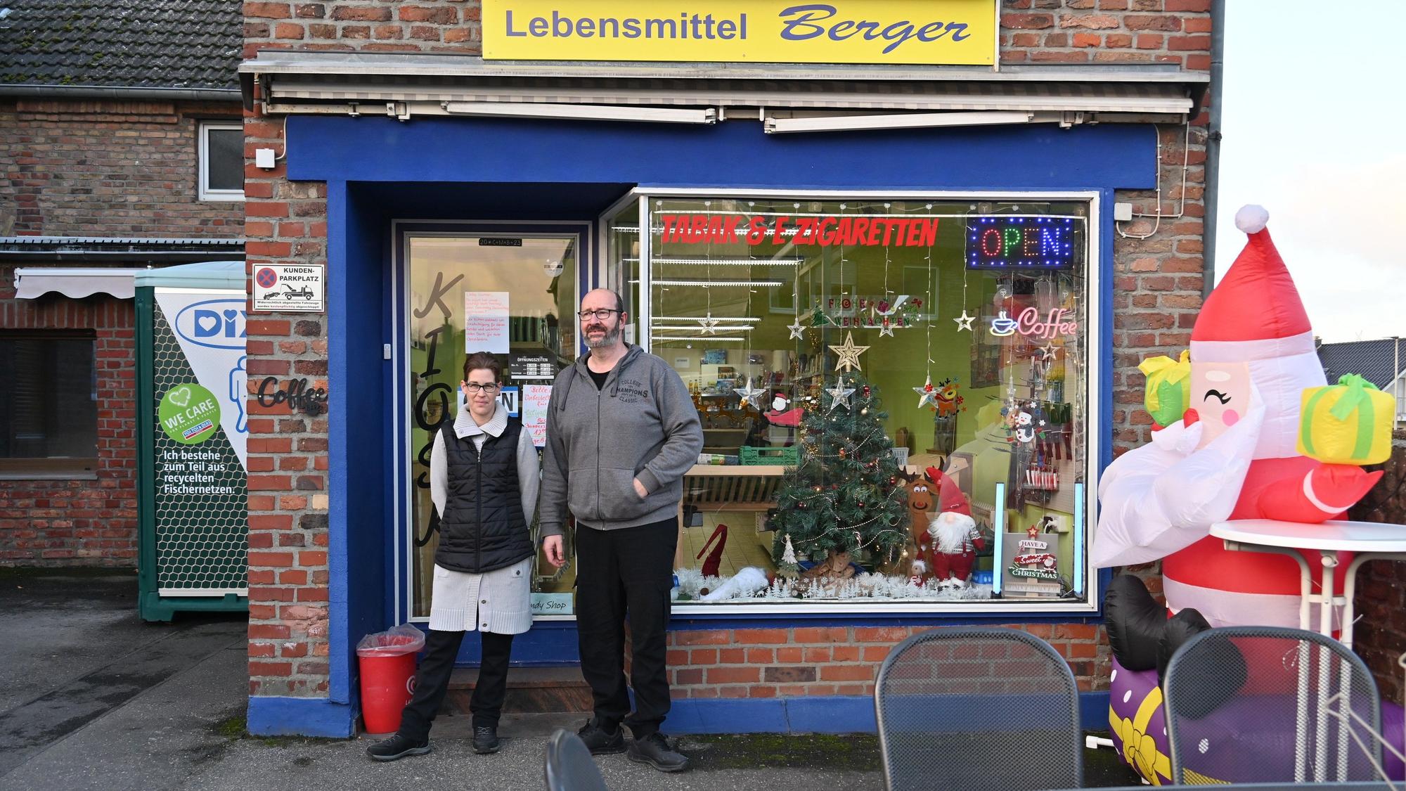 Die Angestellte Yvonne Juris und Jochen Berger stehen vor dem Kiosk, der für die Weihnachtszeit dekoriert ist. Über dem Schaufenster hängt ein Schild mit der Aufschrift Lebensmittel Berger.