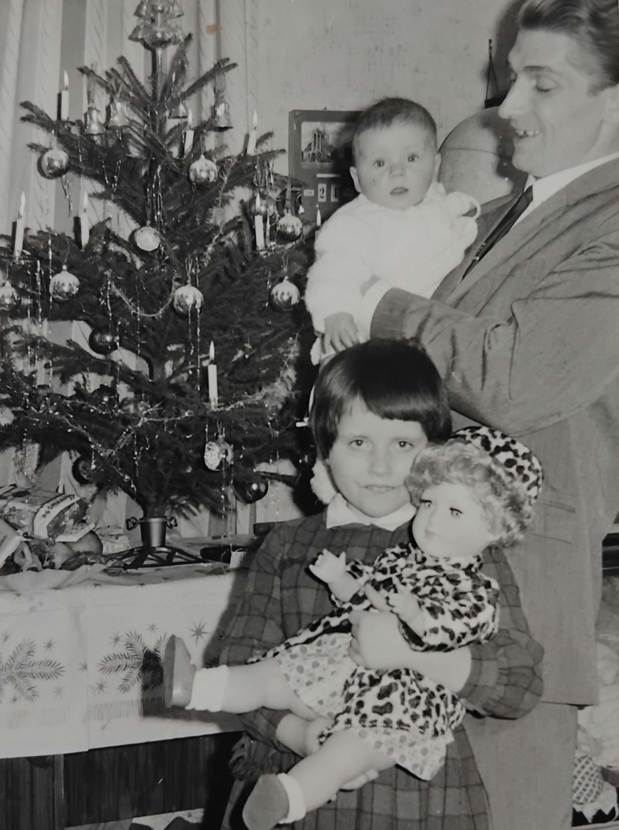 Ein historisches Foto mit einem Mann und zwei Kindern vor einem Weihnachtsbaum